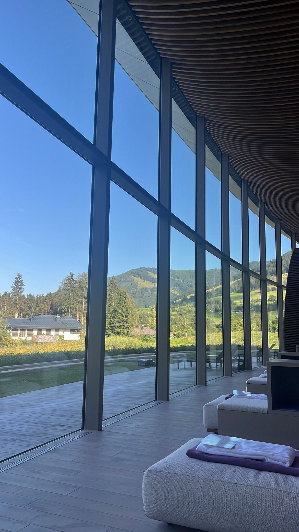 Loungers along the glass wall, and the valley behind them — Hotel Krallerhof